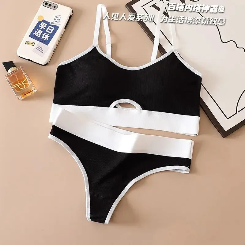 Black and white bikini set on a beige surface with a phone and perfume bottle.
