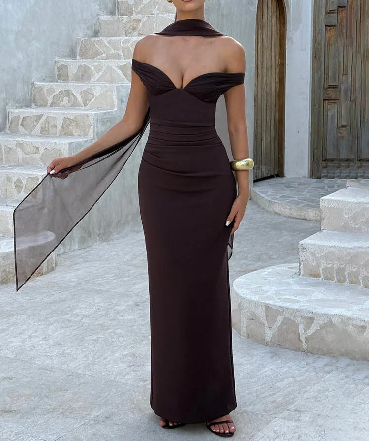 Woman in a dark brown off-shoulder gown standing on stone steps.