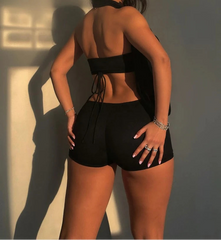 Woman wearing a black outfit with a high back and shorts against a neutral background