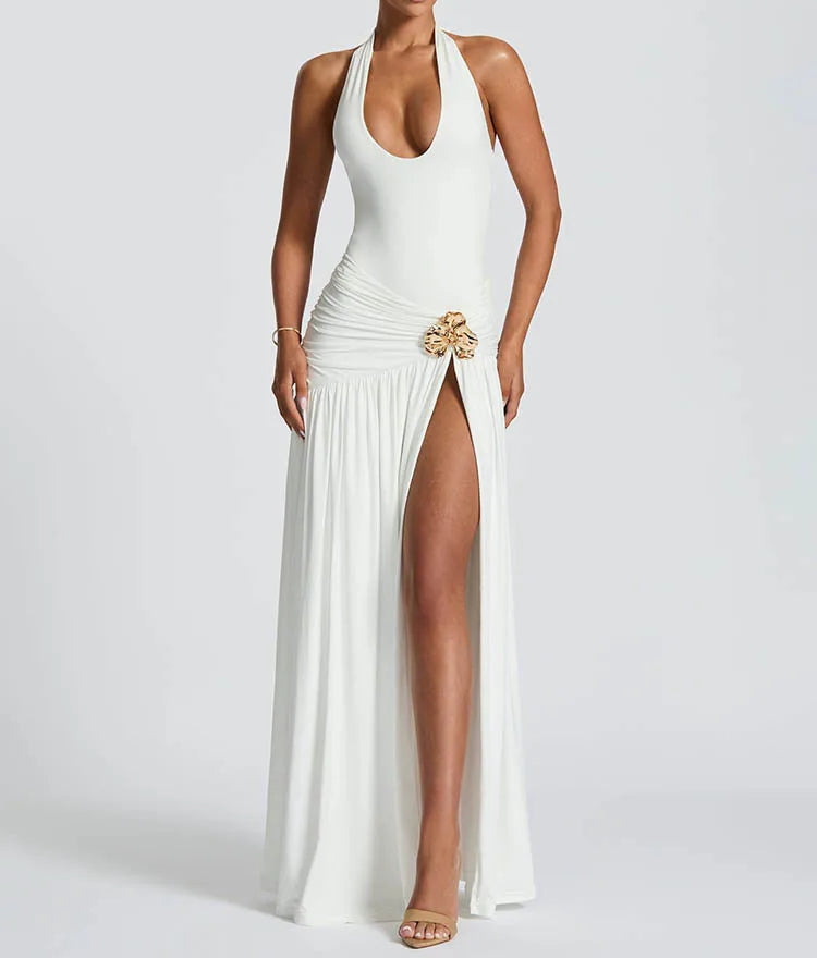 Woman wearing a white halter neck gown with a high slit on a plain background