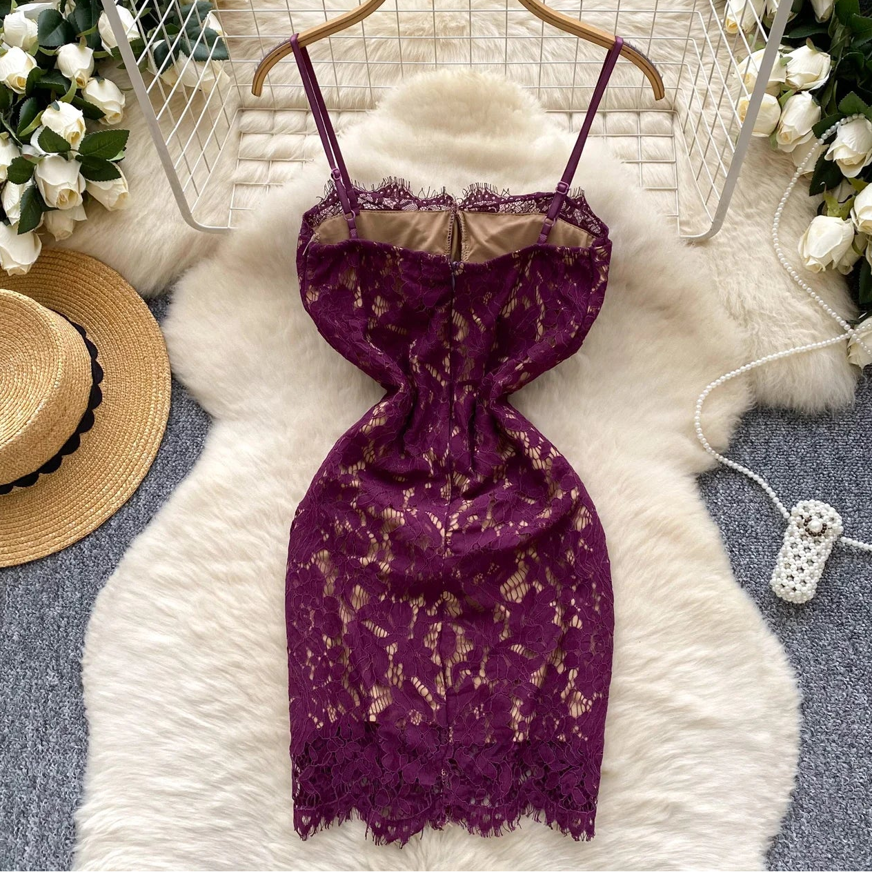 Purple lace dress on a hanger with decorative elements like flowers and a hat.
