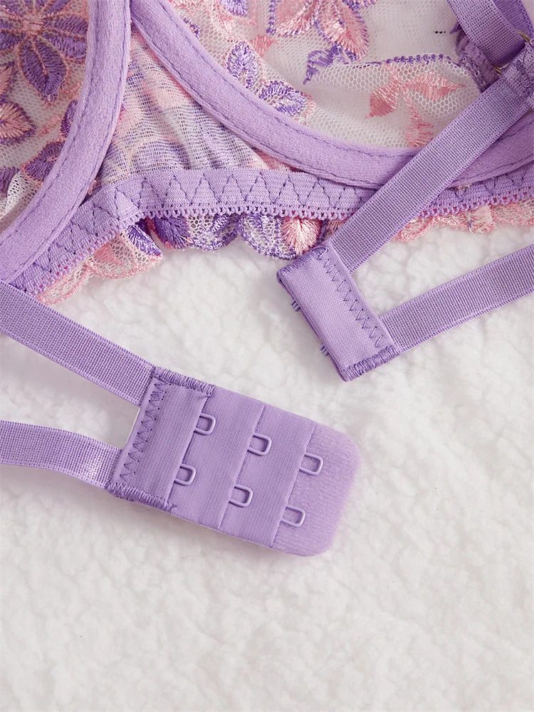Close-up of a purple lace bra and panties set on a textured white surface