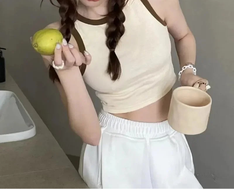 Person holding a green fruit and a small container in a neutral setting