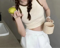 Person holding a green fruit and a small container in a neutral setting