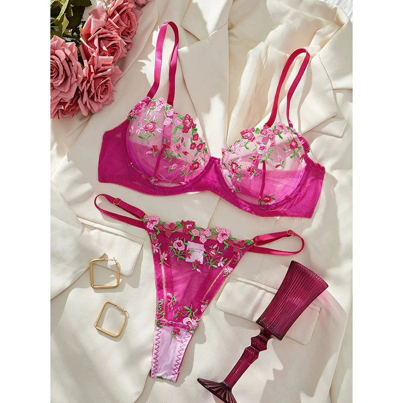 Floral lingerie set on a textured surface with pink flowers and gold jewelry.