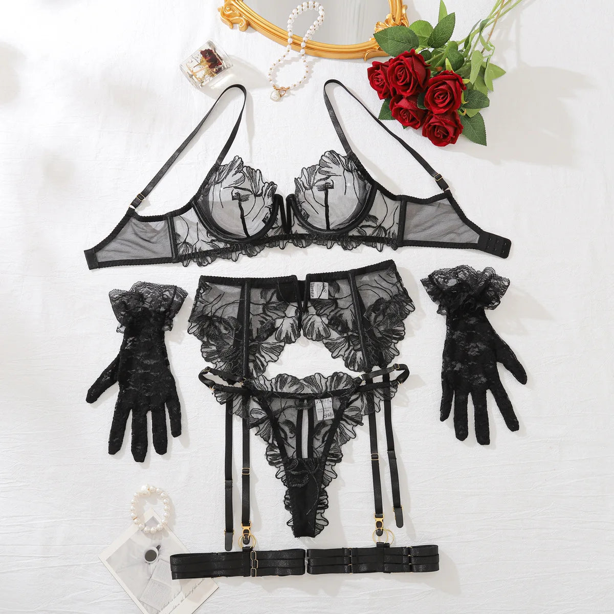 Black lace lingerie set with garter belt, gloves, and bra on a white background.
