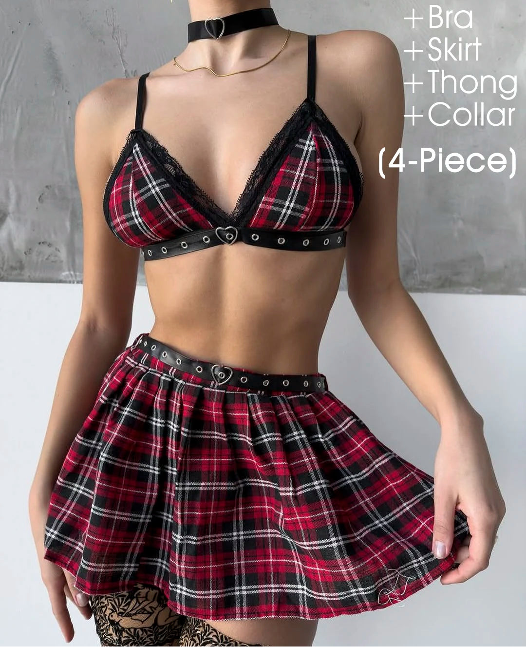 Person wearing a plaid outfit with bra, skirt, thong, and collar on a gray background.