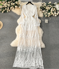 White lace dress on a hanger with decorative flowers and a hat on a gray surface