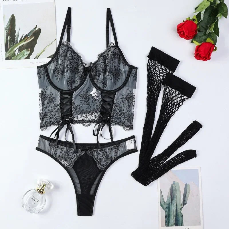 Black lace lingerie set with gloves and a bottle of perfume on a white background