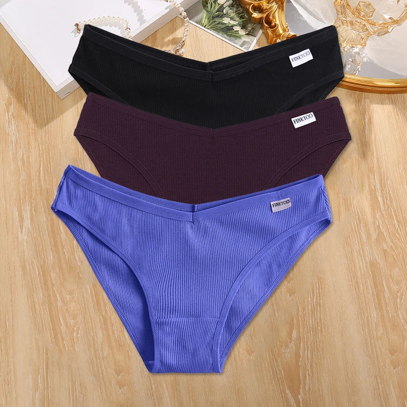 Three pairs of underwear in black, purple, and blue on a wooden surface.