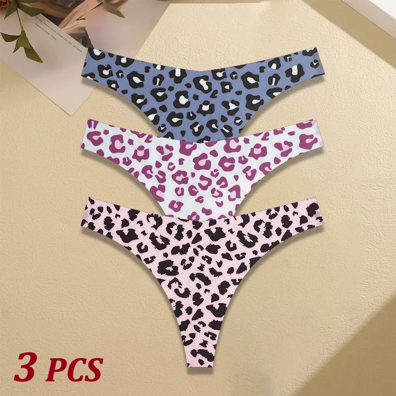 Three leopard print thongs in blue, pink, and purple on a beige surface.