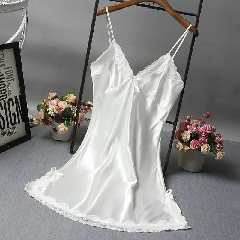 White satin slip dress on a hanger with flowers and a framed picture in the background.