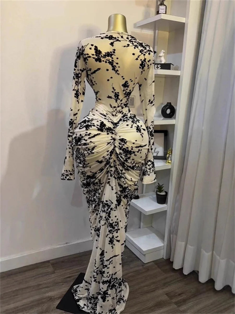 Mannequin wearing a black and white floral dress in a room with a shelf and curtains.