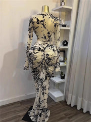 Mannequin wearing a black and white floral dress in a room with a shelf and curtains.