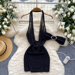 Black dress with a bow on a hanger against a decorative background with flowers and a hat.