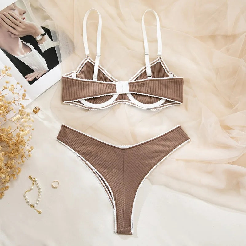 Brown ribbed bikini set on a soft beige fabric background with a blurred photo of a person and jewelry.