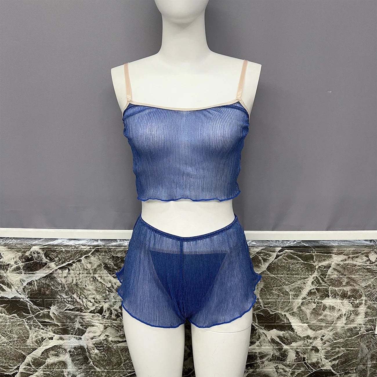 Mannequin wearing a blue sheer top and shorts set against a gray background.