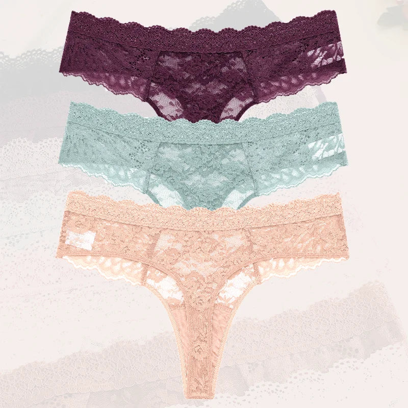 Three pairs of lace underwear in purple, green, and pink on a textured white background.