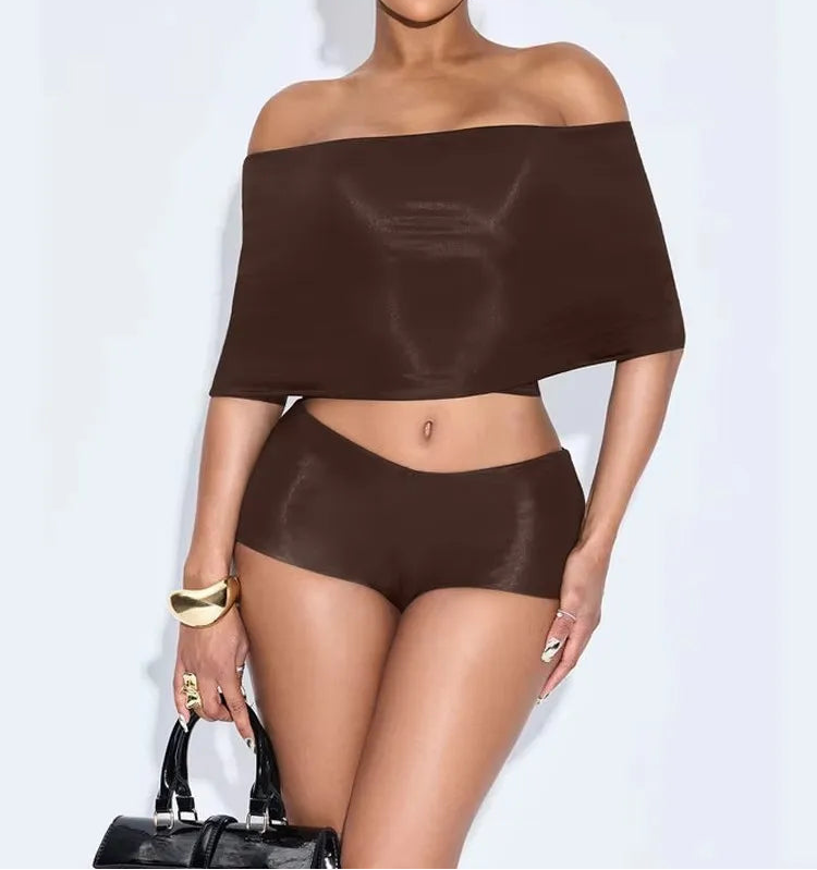 Woman wearing a brown off-shoulder top and high-waisted shorts against a white background