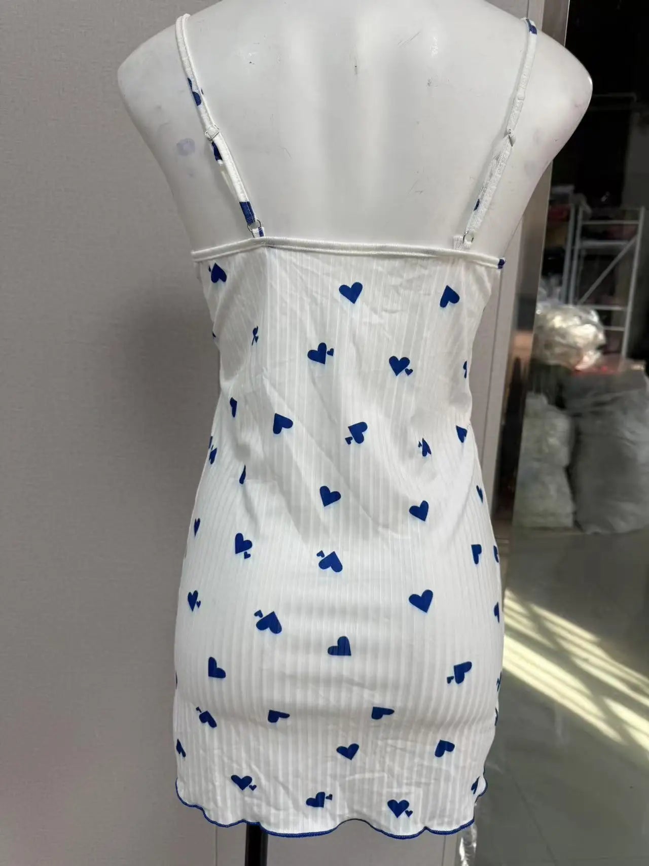 White dress with blue heart patterns on a mannequin against a neutral background