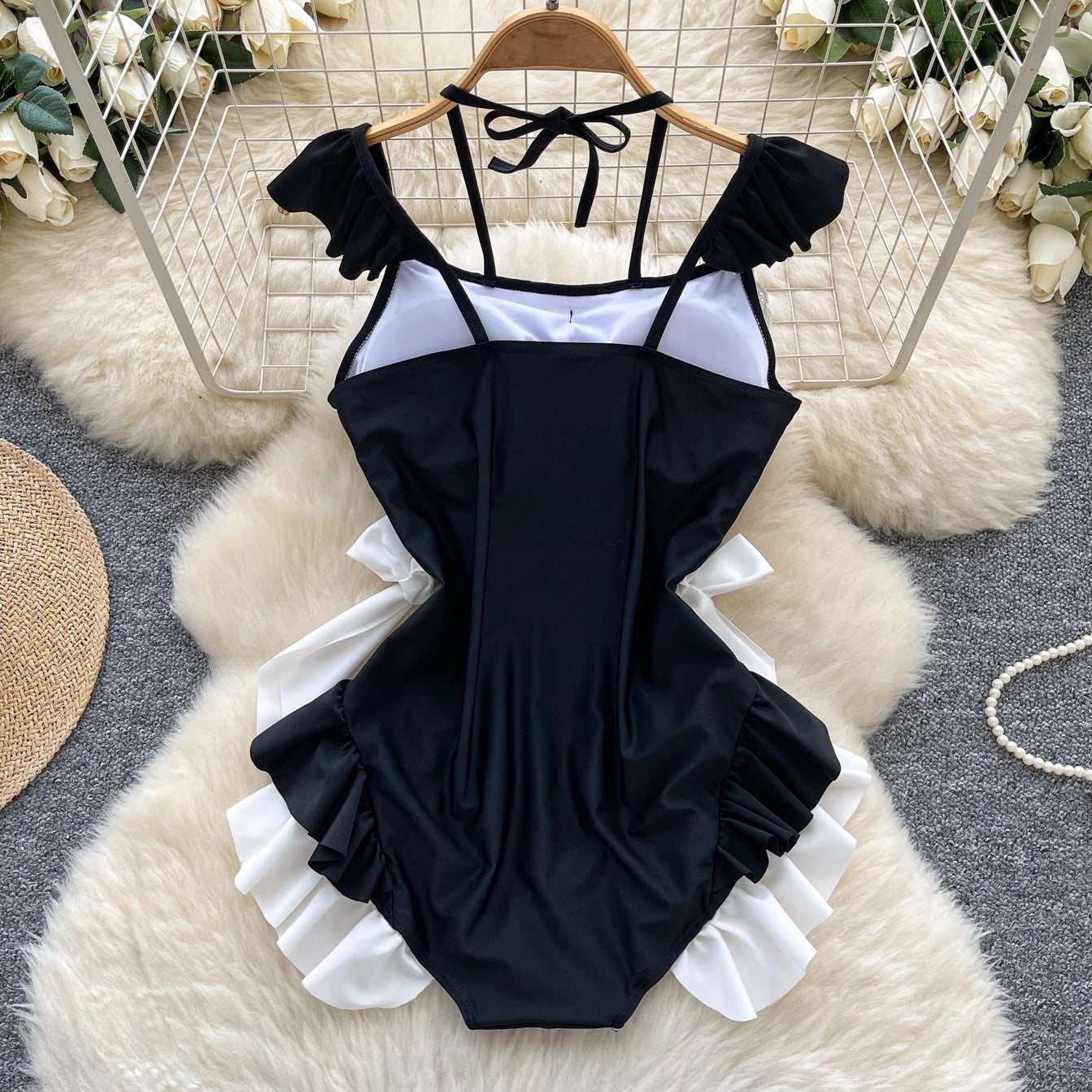Black and white swimsuit on a hanger with decorative background