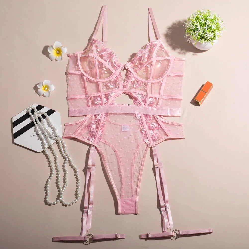 Pink lace lingerie set on a beige background with decorative items.