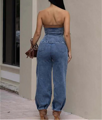 Woman wearing a strapless denim jumpsuit walking outdoors.
