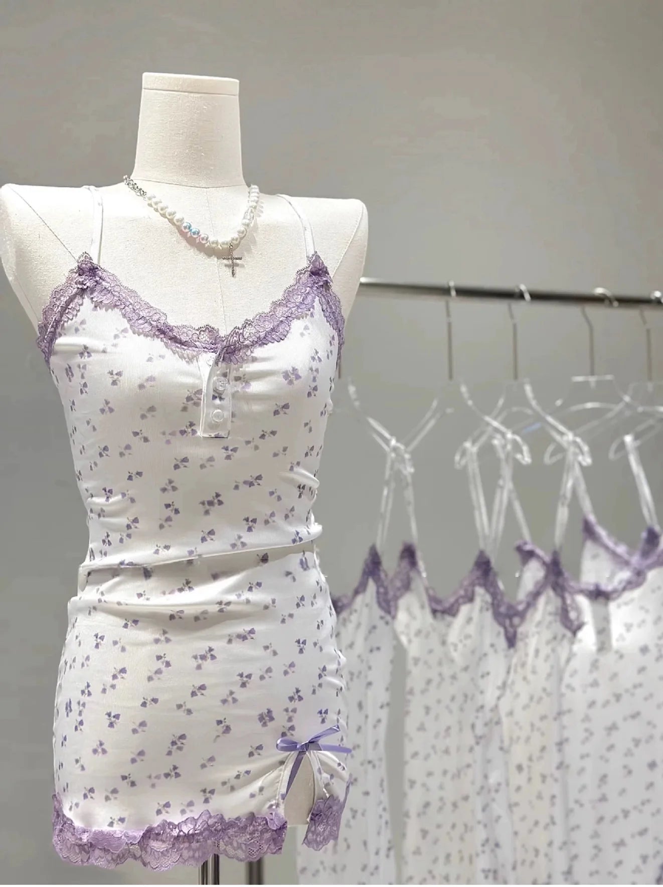 White dress with purple lace details on a mannequin against a plain background
