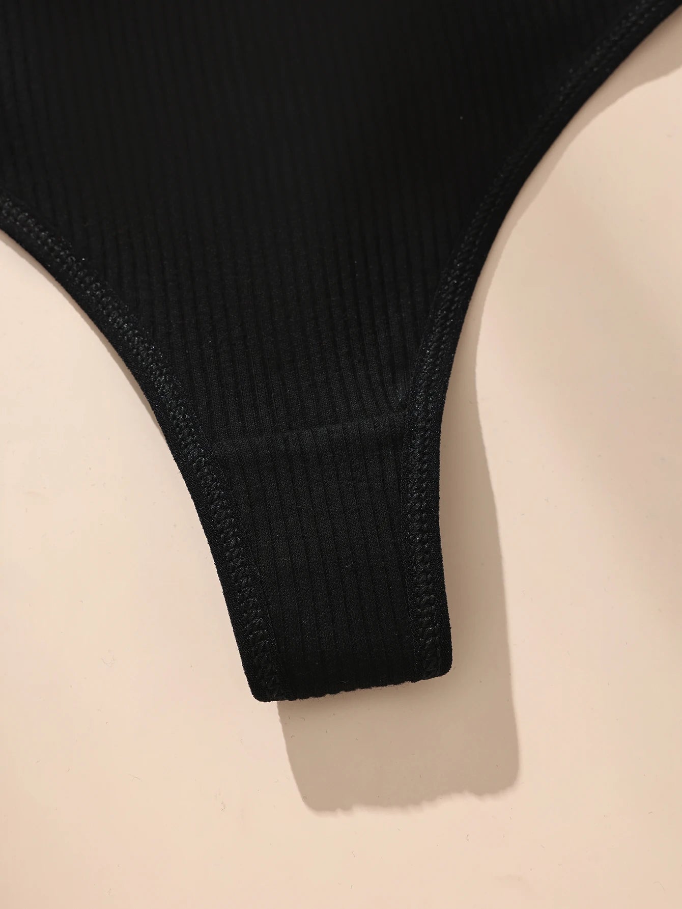 Black ribbed knit garment on a beige background