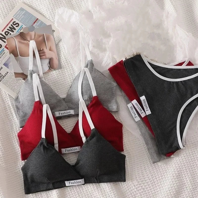 Four bras in red, gray, and black on a textured surface with a magazine in the background.