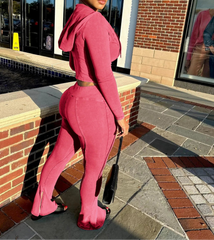 Person wearing a pink outfit standing on a sidewalk.