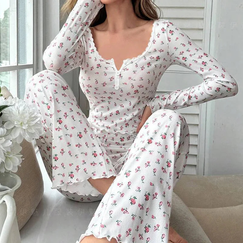 Woman wearing a white floral pajama set sitting on a couch.