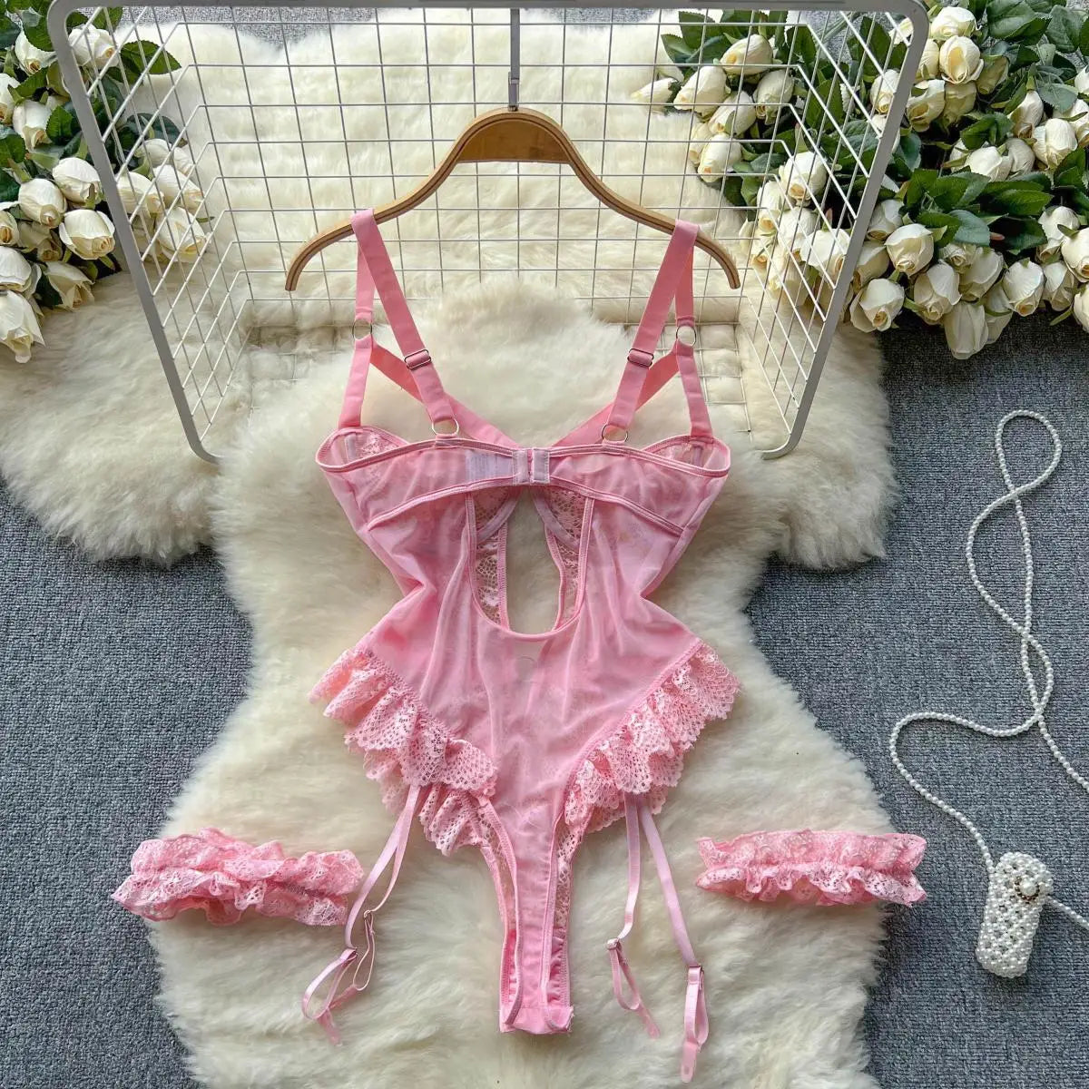 Pink lace lingerie set on a white fur rug with floral decorations.