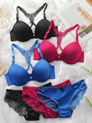 Four pairs of women's underwear laid flat on a white fabric background: two bras in black and blue with lace straps, and two panties in black and bright pink with lace trim. No person, animal, or real environment is present.
