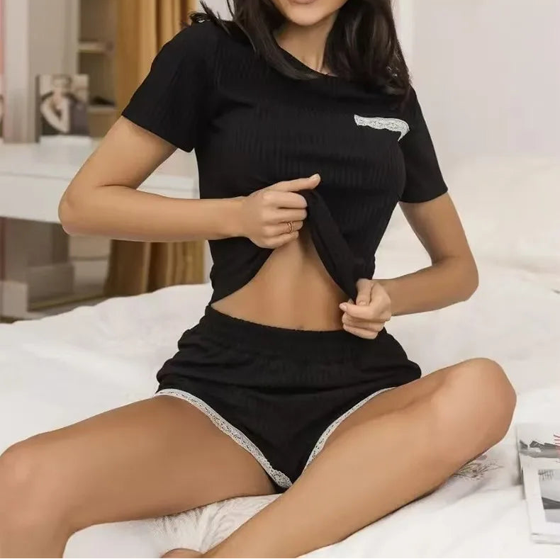Woman wearing a black outfit sitting on a bed in a well-lit room.