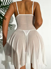 Woman wearing a sheer white dress with thin straps against a neutral background