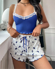Woman wearing a blue top and white floral shorts with blue accents.
