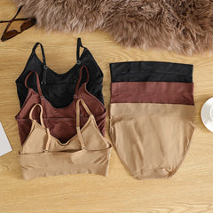 Set of women's lingerie including a black top, brown bralette, and beige panties on a wooden surface.