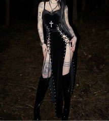 Person wearing a black gothic outfit with tattoos standing in a dark forest.