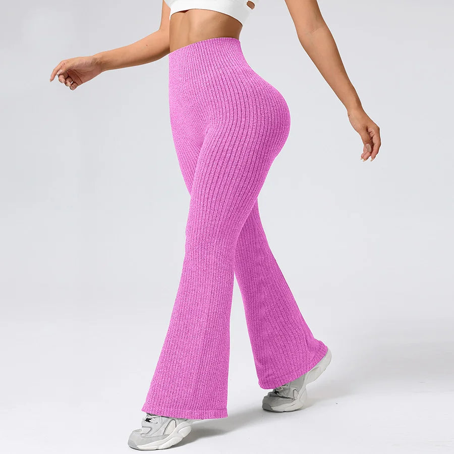 Person wearing bright pink ribbed knit pants on a plain background