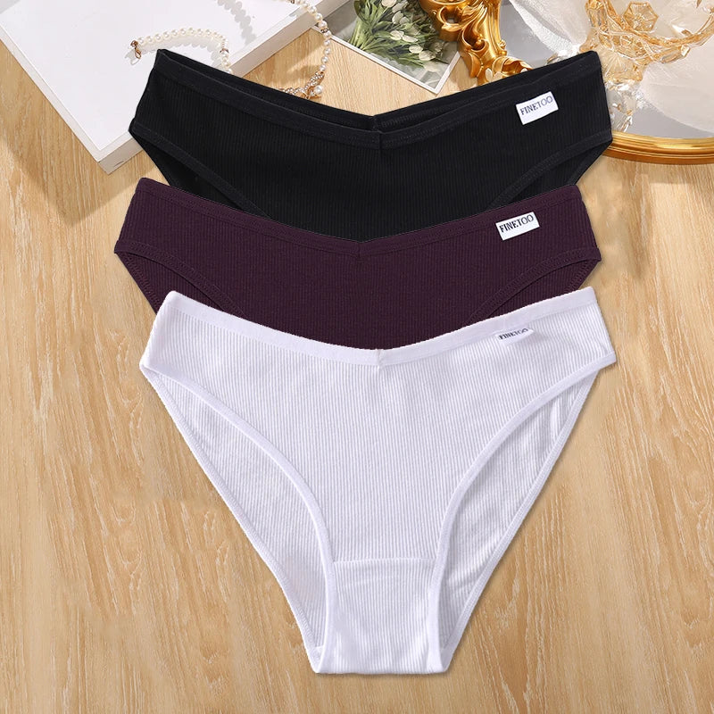 Three pairs of underwear in black, purple, and white on a wooden surface.