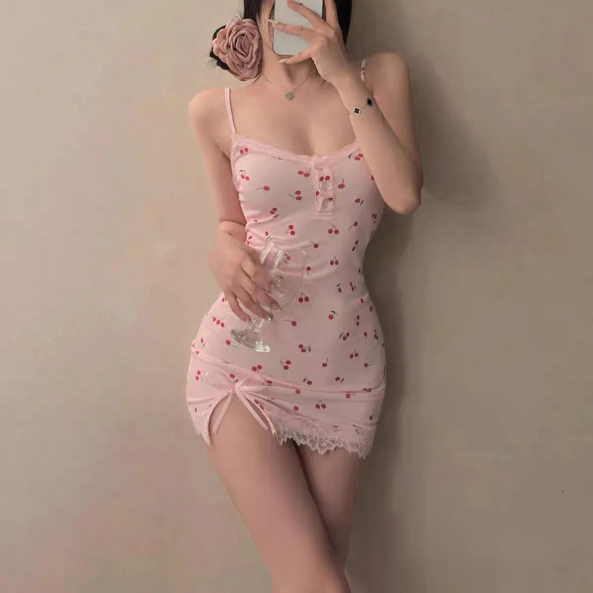 Person wearing a pink lace nightgown holding a glass against a plain background