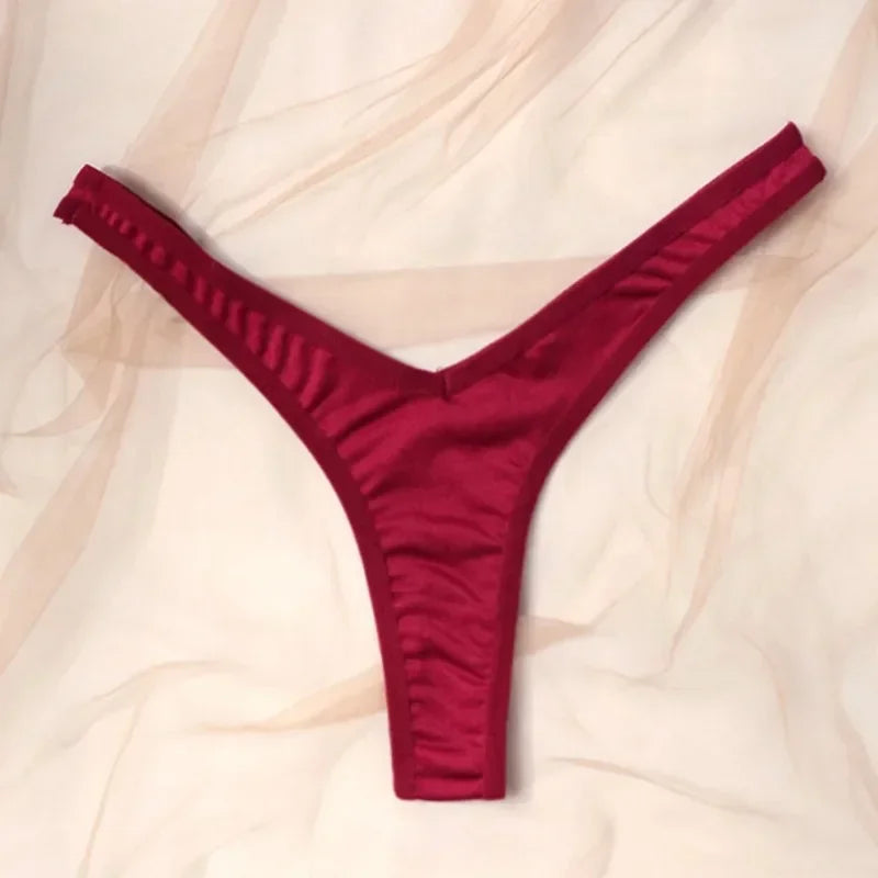 Red thong underwear on a light pink fabric background