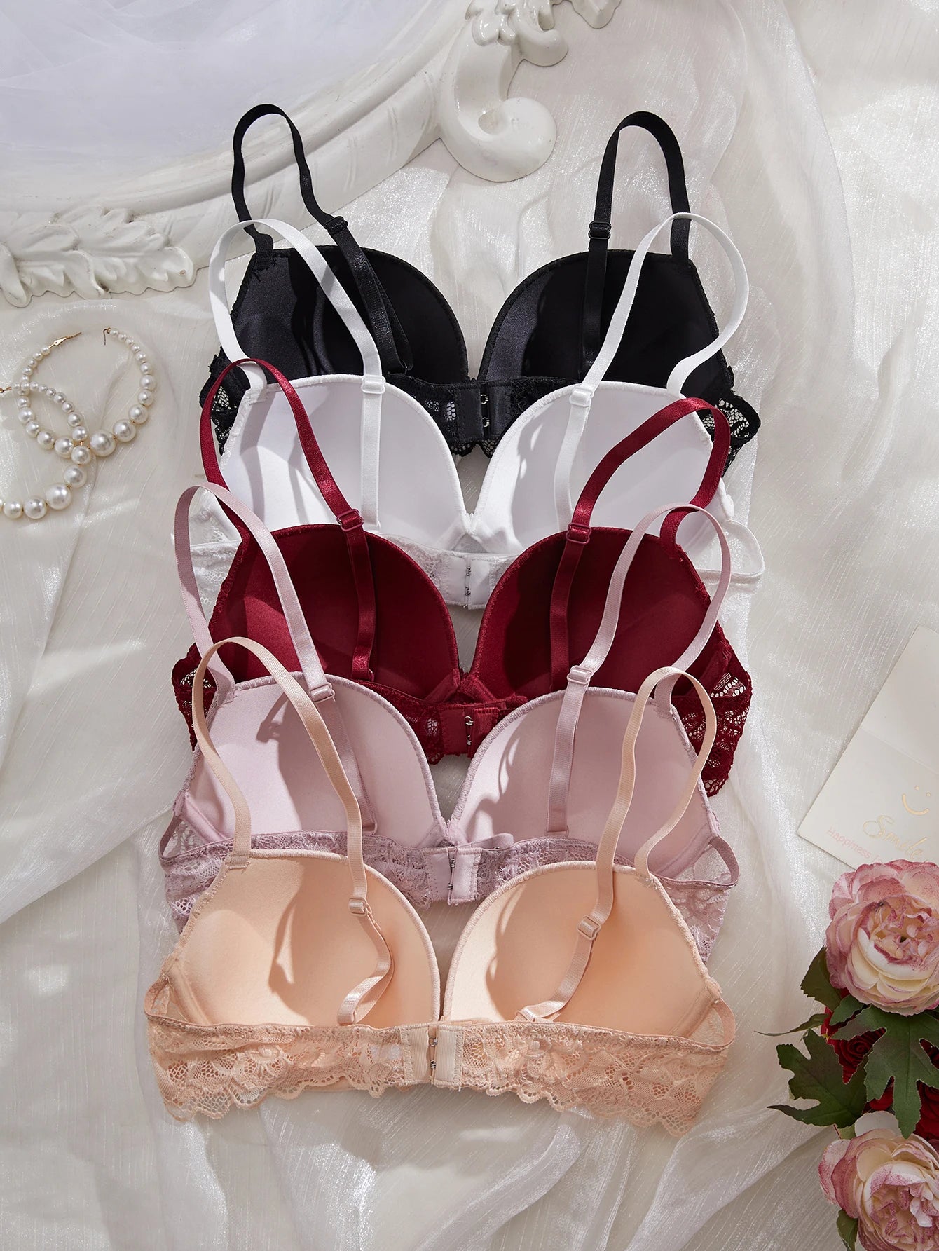 Set of three bras in black, red, and beige on a decorative background with flowers.