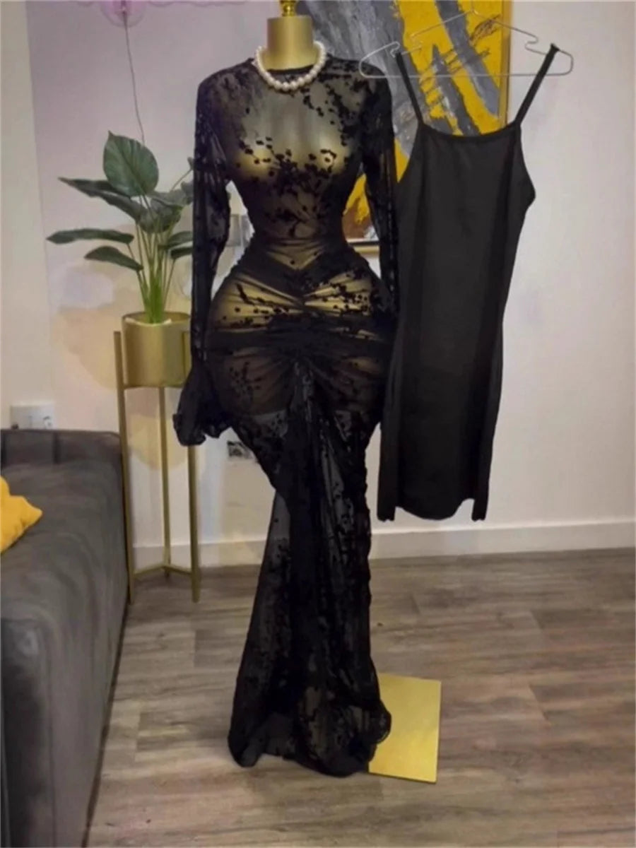 Black lace evening gown on a mannequin in a room with a plant and sofa.