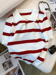 Red and white striped sweater on a surface with a magazine in the background