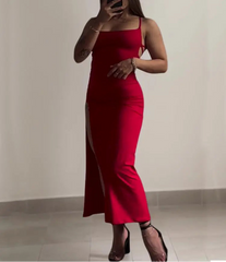Person wearing a red dress with a slit, standing against a plain background.