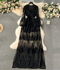 Black lace dress on a hanger with flowers and a hat in the background