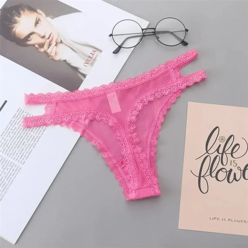 Pink lace lingerie on a gray surface with a magazine and eyeglasses.