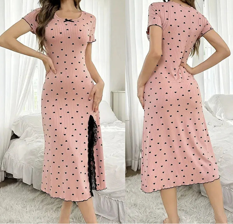 Pink dress with black heart patterns worn by a model in a bedroom setting